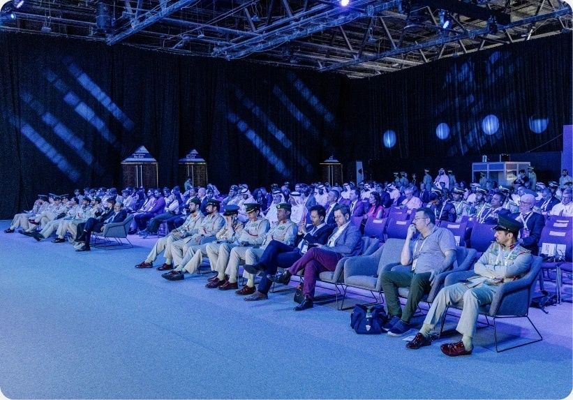 Grote, geordende congreszaal met publiek en geüniformeerde aanwezigen